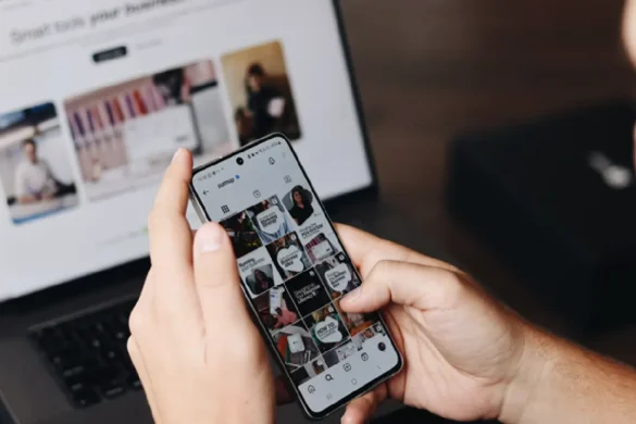 Person browsing social media on a smartphone beside a laptop.